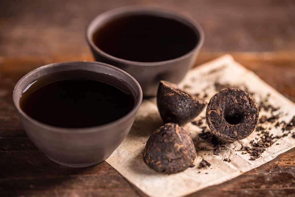 Cups of black tea with pressed tea leaves